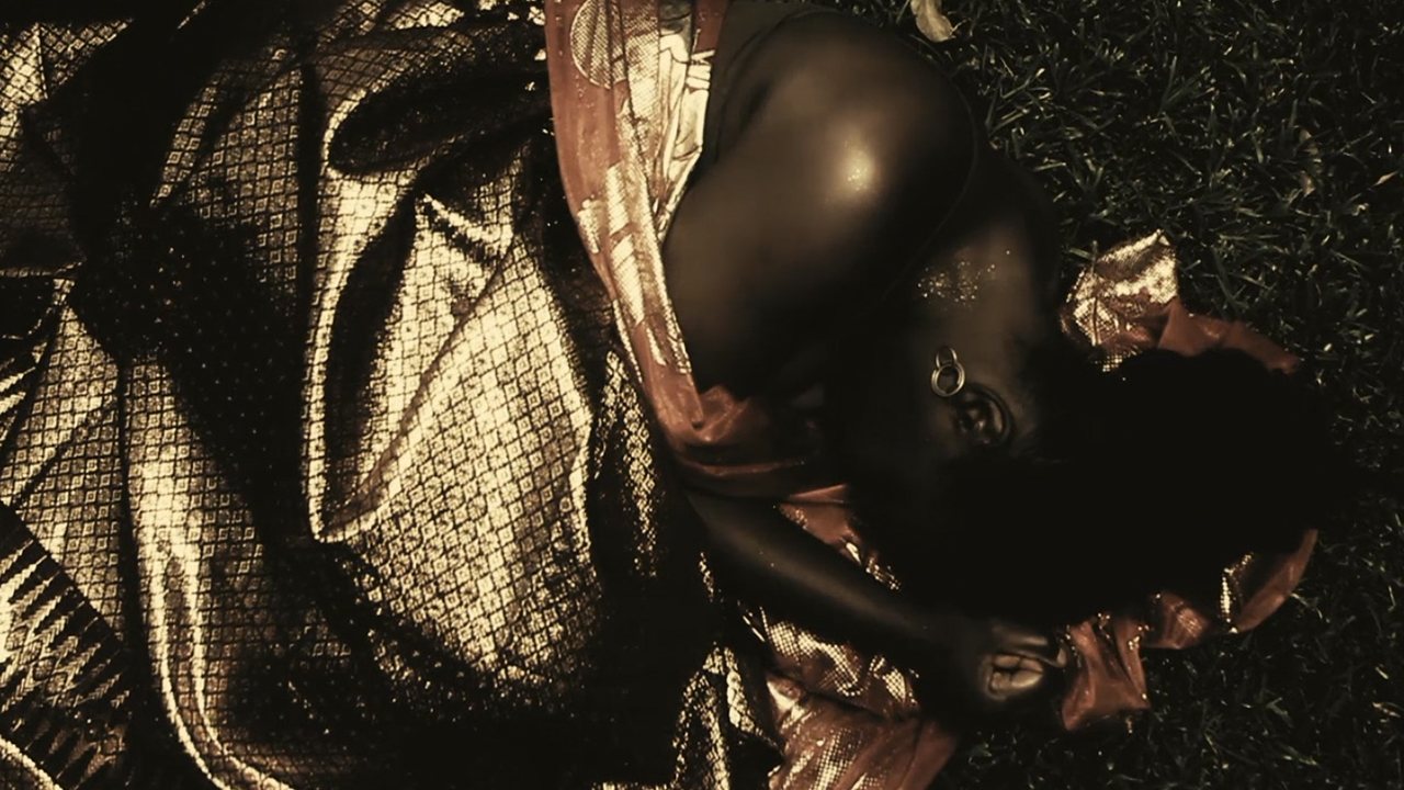 Overhead shot of a figure lying in gold cloth on grass