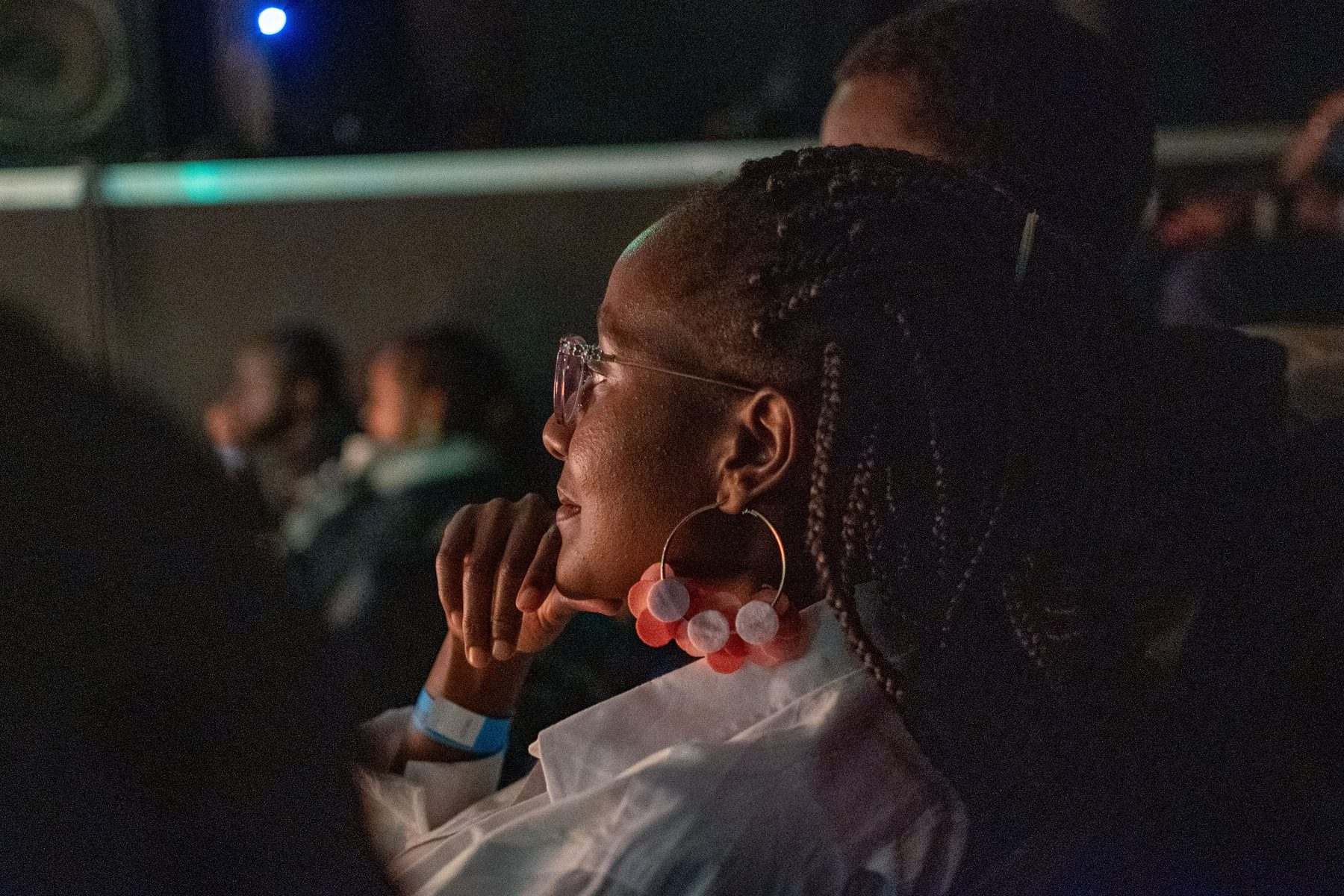 An audience member watches the performance, chin resting on her hand